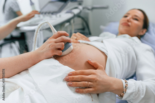 Pregnant woman is lying down in the hospital, doctor does ultrasound