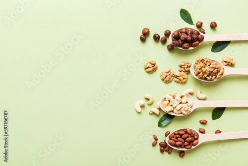 mixed nuts in white wooden spoon. Mix of various nuts on colored background. pistachios, cashews, walnuts, hazelnuts, peanuts and brazil nuts