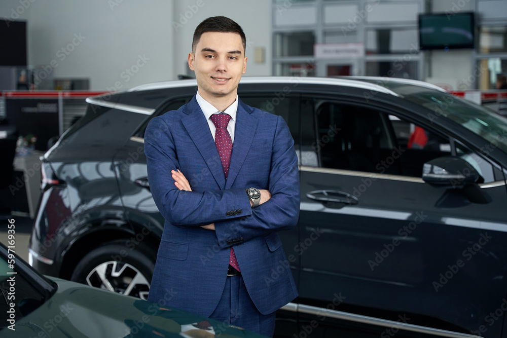 Pleasant man stands against the backdrop of a shiny car Pleasant man stands against the backdrop of a shiny car