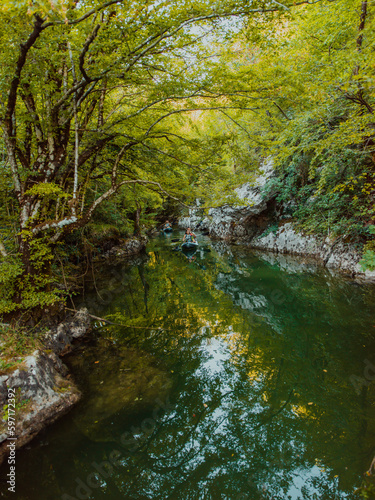 A group of friends enjoying having fun and kayaking while exploring the calm river, surrounding forest and large natural river canyons