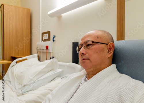A hospital patient sitting in an armchair in a private room waiting for surgery.