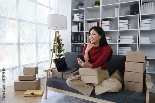 Portrait of young beautiful online business owner sitting in the room full of boxes, thinking about the next move of the business.