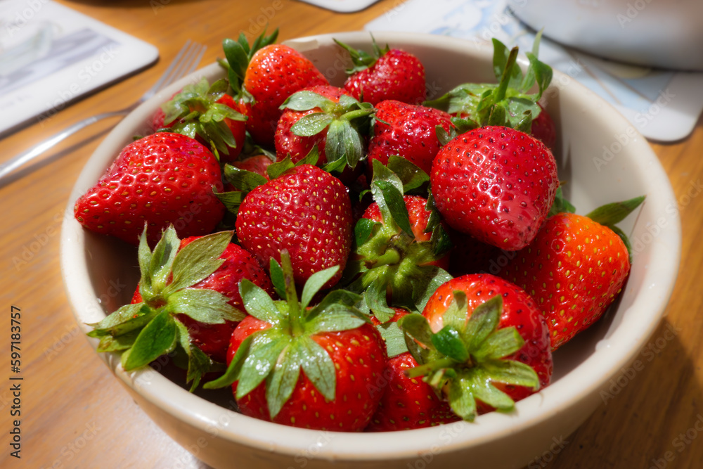 Close up view of a bowl of fresh strawberries on a dining table Close up view of a bowl of fresh strawberries on a dining table