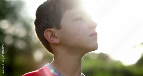 Young boy looking up to the sky with hope and faith. Thoughtful child