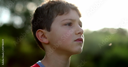 Thoughtful contemplative child looking up to the sky with hope and faith. Pensive young boy