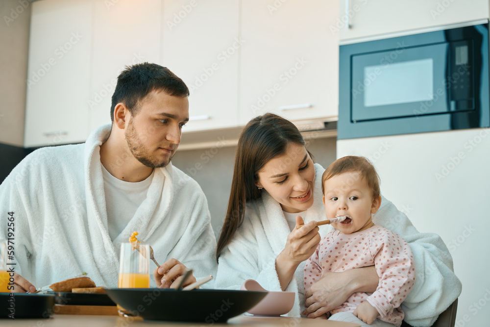 Happy young family at breakfast, at the table mom Happy young family at breakfast, at the table mom