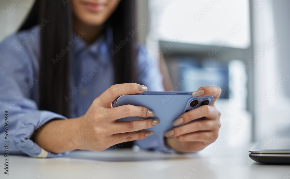 Young girl playing online games on a smartphone. Unrecognizable female person plays video games on a modern gadget Young girl playing online games on a smartphone. Unrecognizable female person plays video games on a modern gadget