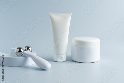 A face massaging roller made of steal and a tube of cream mockup, presenting product. Mockup cream. Branding. Copy space