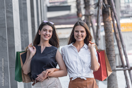 Young shopaholic friends women friends walking and carry shopping bags in the street city with happy and smiling.