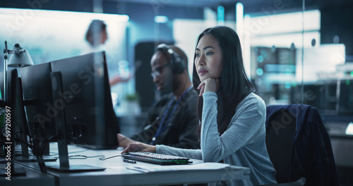 Portrait of a Thoughtful Asian Engineer Working on Computer in a Technological Corporate Laboratory. Young Woman Writing Software Code for an Innovative Internet and Software as a Service Project
