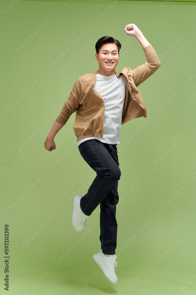 Full size photo of young happy excited crazy positive man jumping hold fists in victory