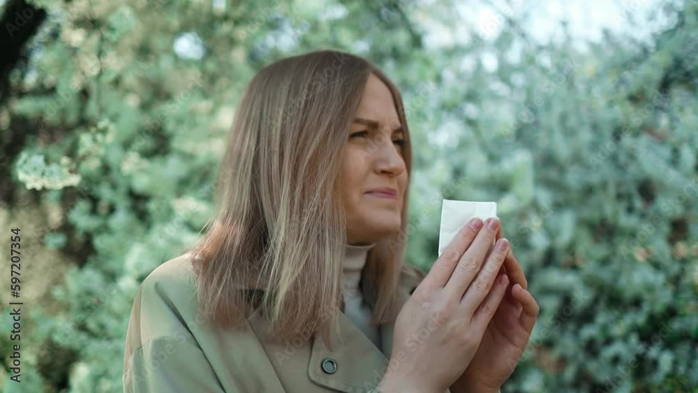 Young pretty woman sneezing in front of blooming tree. Spring allergy concept. High quality FullHD footage Young pretty woman sneezing in front of blooming tree. Spring allergy concept. High quality FullHD footage