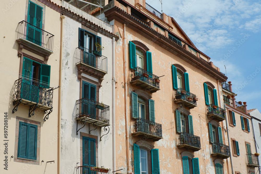 Facade of a vintage buildings downtown Bosa, Sardinia, Italy. Shutters on the windows, Italian aesthetics