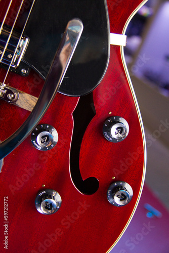 Close up of a hollow body red electric guitar with humbucker pickups, black pickguard and silver hardware. photo