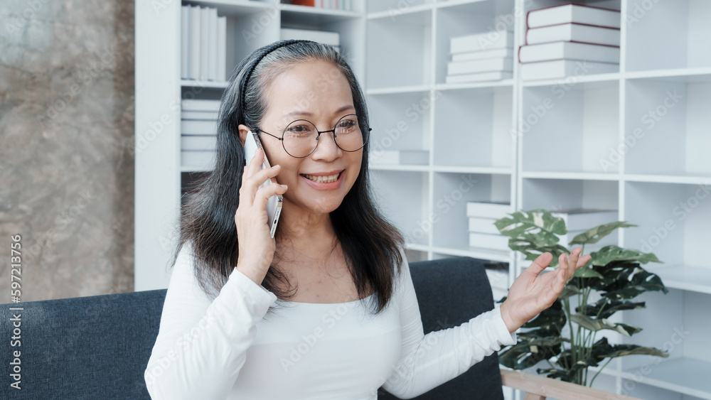 Call a mobile cellphone, Happy asian mature woman people relaxing while sitting on a couch Call a mobile cellphone, Happy asian mature woman people relaxing while sitting on a couch