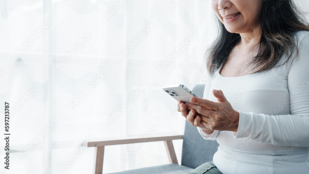 Using mobile, shopping online with credit card, Happy asian mature woman people relaxing while sitting on a couch Using mobile, shopping online with credit card, Happy asian mature woman people relaxing while sitting on a couch
