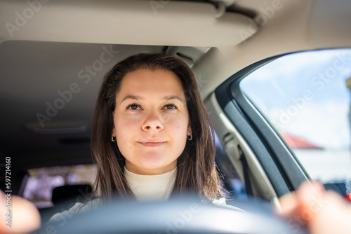 Happy woman driving a car and smiling. Cute young success happy brunette woman is driving a car. Portrait of happy female driver steering car.