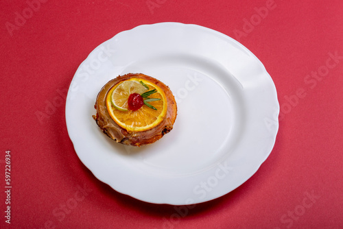 Cheese cake with marmalade and lime and orange slices in a white plate on a red background