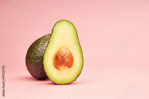 Avocado half part with the pit isolated on the bright solid fond plain pink background