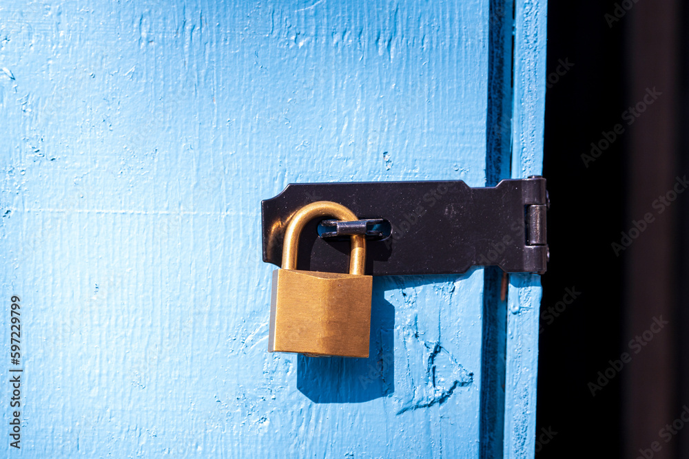 Ταπετσαρία brass padlock securing a black metal hasp on a blue wooden door room for text