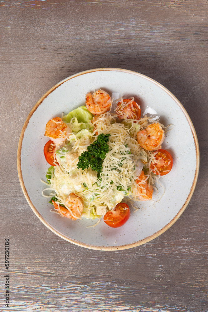 Shrimp salad in a plate on a brown background.