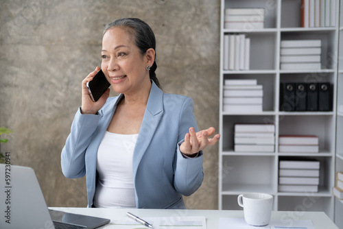 Senior businesswoman talking on phone while sitting in the office room.