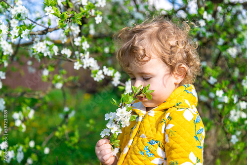 A child in the garden sniffs a blossoming spring tree. Selective focus.