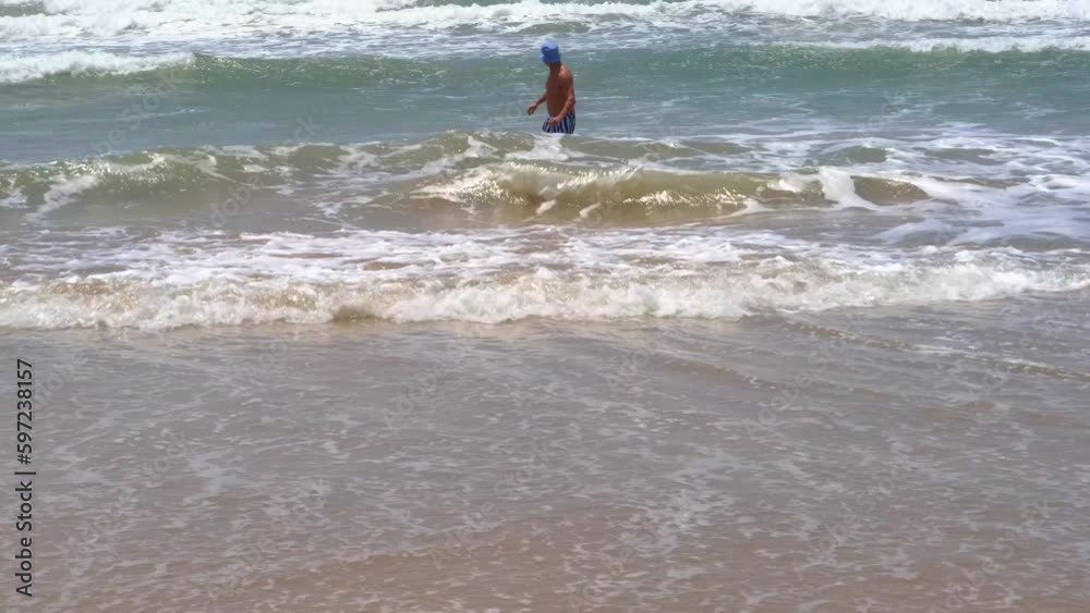 happy mature man, healthy senior 60 years old in ocean waves, swims in open sea, improve health, concept dangers of rips, learning swimming skills, vacation and travel, climate change, global warming happy mature man, healthy senior 60 years old in ocean waves, swims in open sea, improve health, concept dangers of rips, learning swimming skills, vacation and travel, climate change, global warming