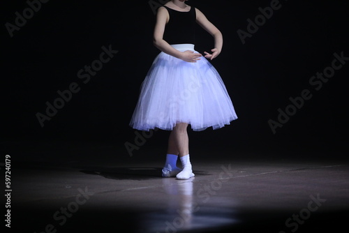 A ballet dancer in a pose dancing on a black stage
