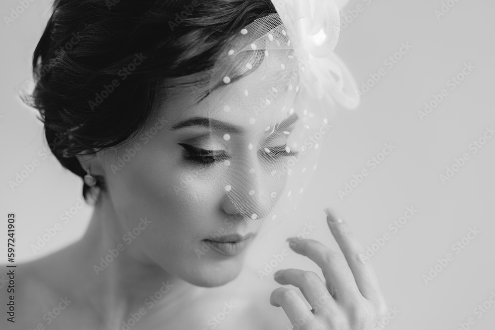 An elegant woman in veil hat posing for camera with closed eyes