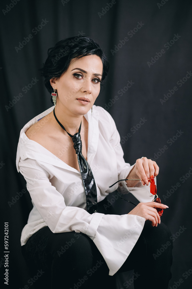 A fashionable woman in a white shirt holding a glamorous glass and striking a confident pose for the camera
