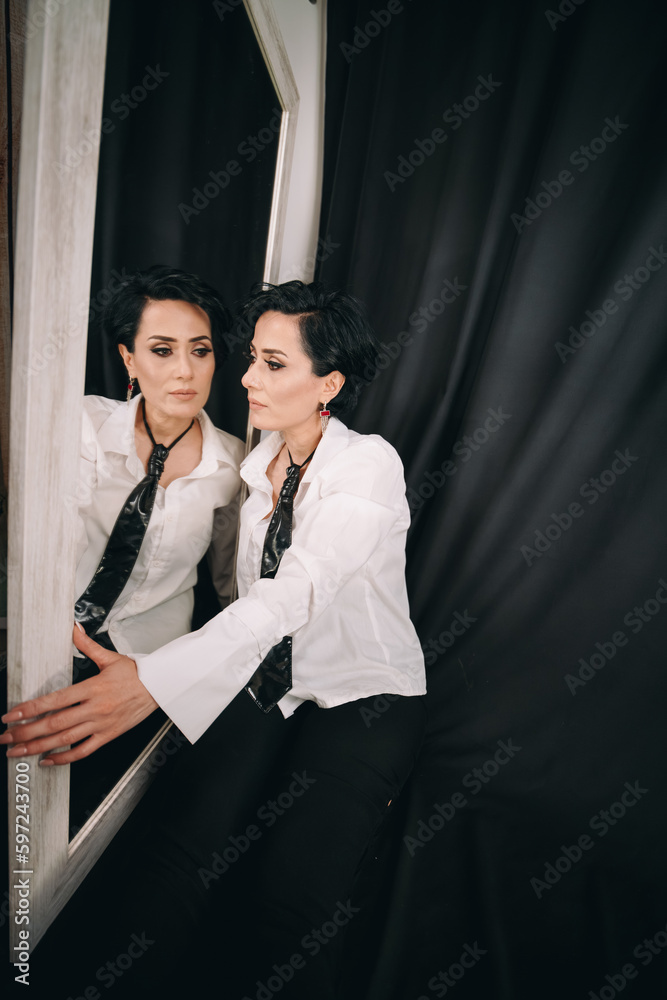 Confident, radiant woman in white shirt posing with a mirror and examining her reflection