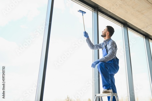 Young man cleaning window in office