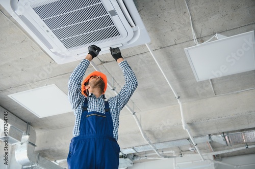 Obraz na płótnie specialist cleans and repairs the wall air conditioner