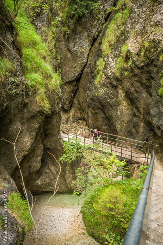 Caucasian man posing on a metal bridge in a german canyon called Almbachklamm during summer. View from above