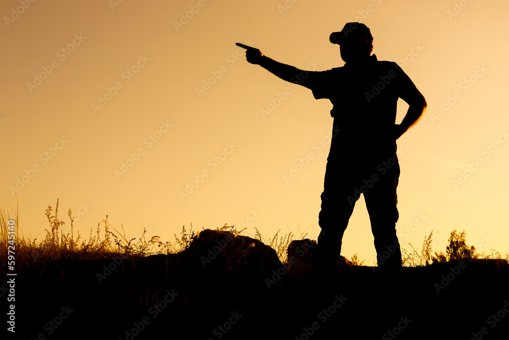 the silhouette of a man in a cap points with his hand to the left direction or something