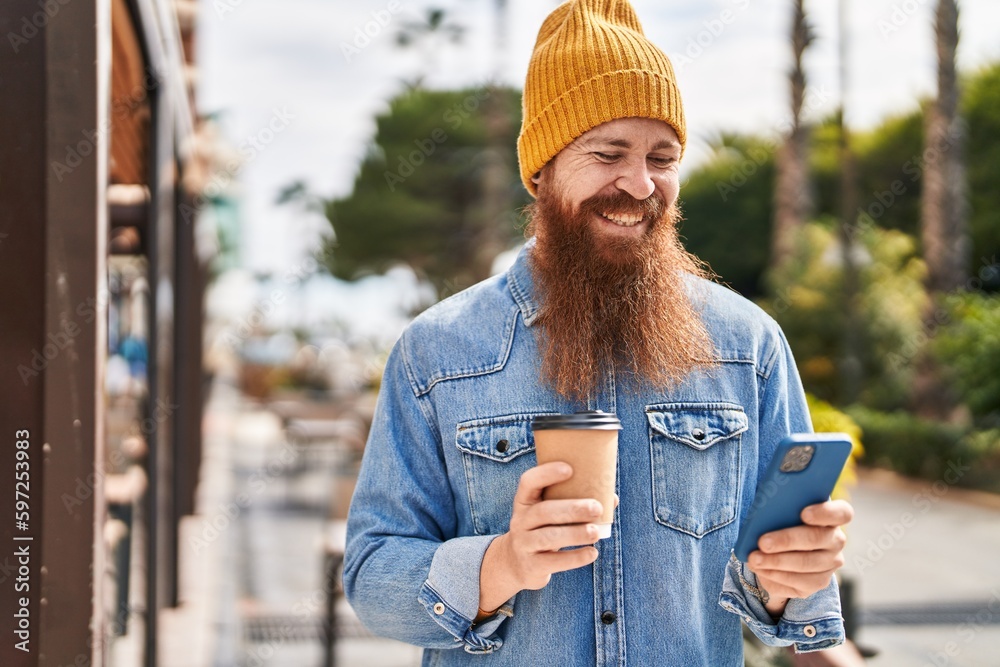 Young redhead man using smartphone drinking coffee at street