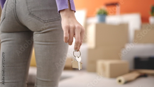Young blonde woman holding key standing at new home