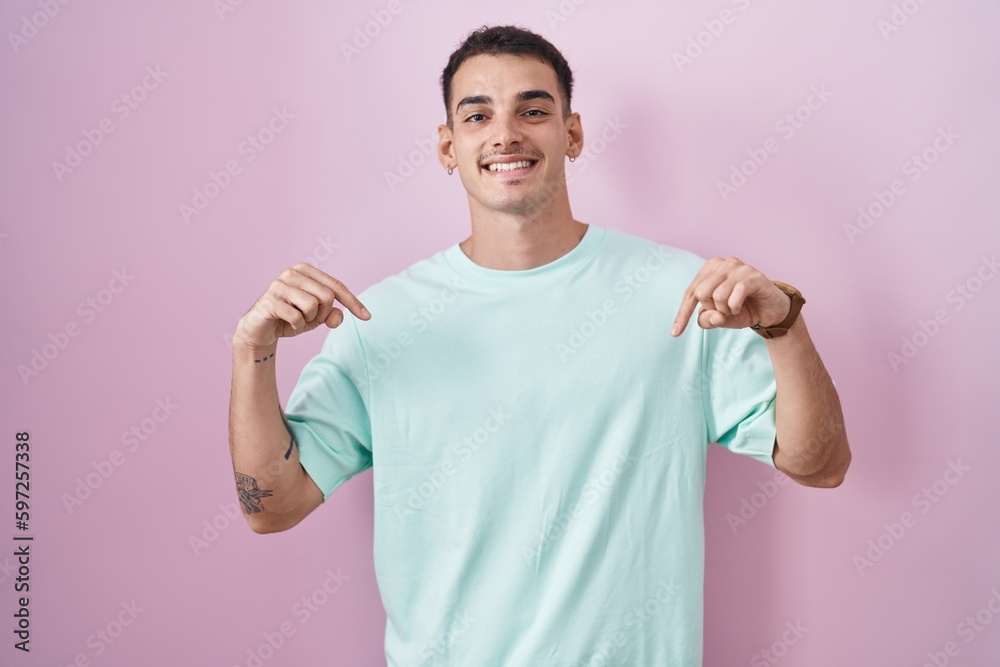 Handsome hispanic man standing over pink background looking confident with smile on face, pointing oneself with fingers proud and happy. Handsome hispanic man standing over pink background looking confident with smile on face, pointing oneself with fingers proud and happy.