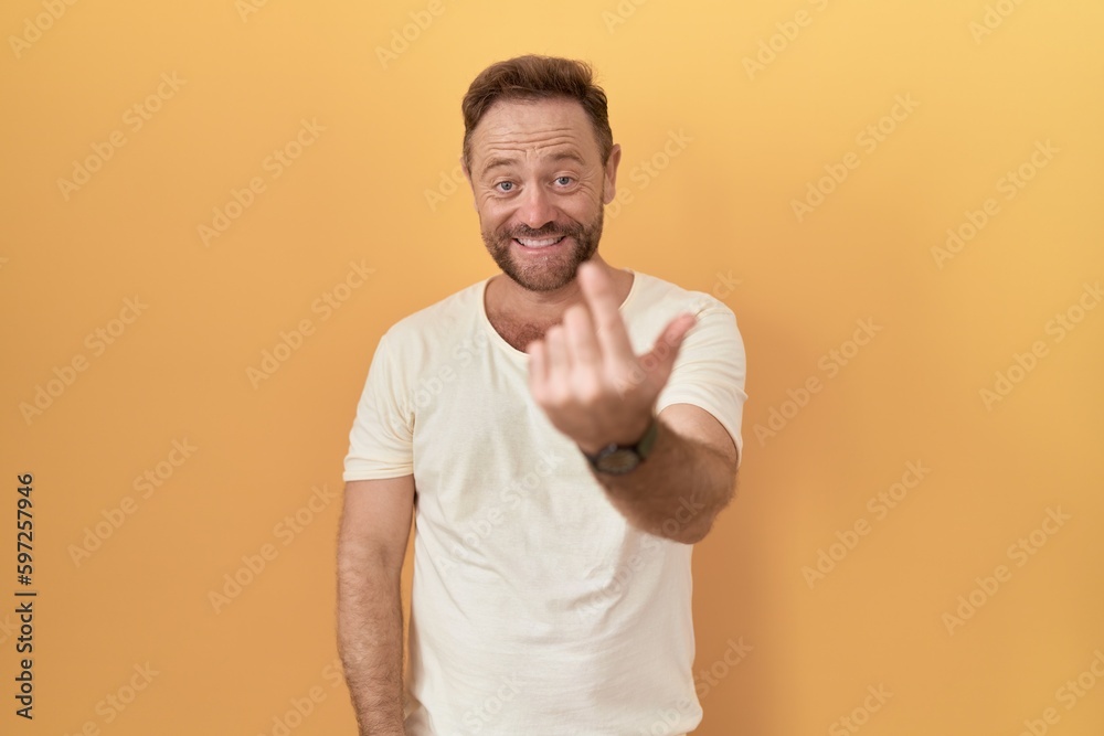 Middle age man with beard standing over yellow background beckoning come here gesture with hand inviting welcoming happy and smiling Middle age man with beard standing over yellow background beckoning come here gesture with hand inviting welcoming happy and smiling