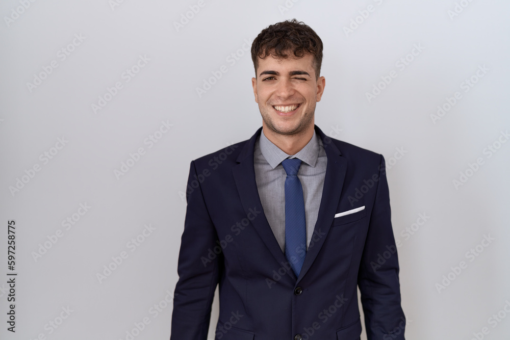 Young hispanic business man wearing suit and tie winking looking at the camera with sexy expression, cheerful and happy face. Young hispanic business man wearing suit and tie winking looking at the camera with sexy expression, cheerful and happy face.