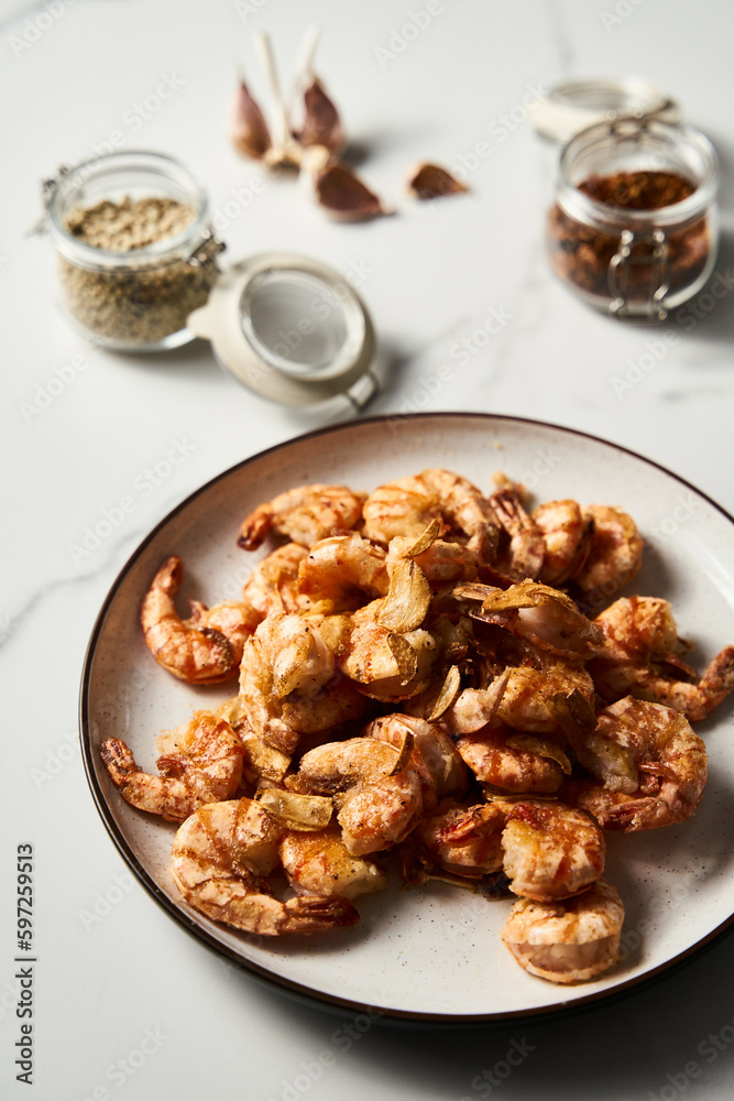 Crispy Pan fried tiger shrimps or prawns with garlic. Chinese or Asian cuisine dish. Shrimps lay on white plate on white marble background. T Crispy Pan fried tiger shrimps or prawns with garlic. Chinese or Asian cuisine dish. Shrimps lay on white plate on white marble background. T