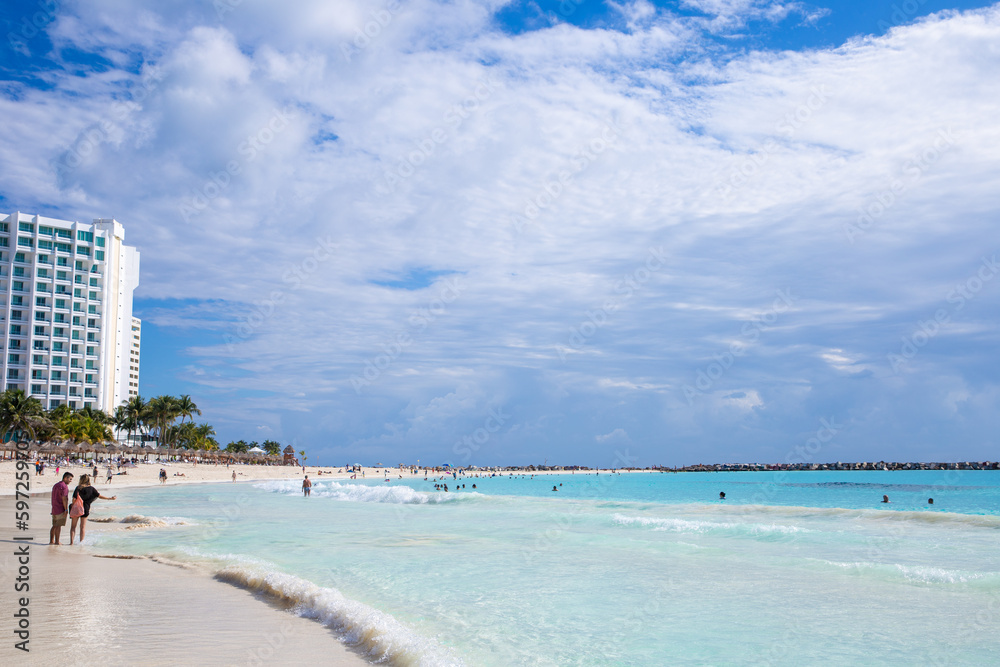 Beautiful sandy beach with people relaxing in a resort in Cancun, Mexico. Summer and sunshine.