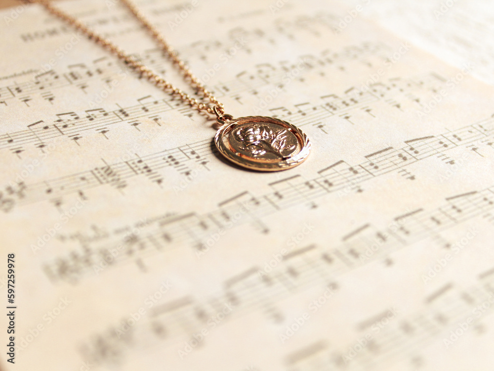 A necklace on a old music sheet background. Vintage fashion concept and jewelry minimalist style. Close-up. Autumn colors composition. A necklace on a old music sheet background. Vintage fashion concept and jewelry minimalist style. Close-up. Autumn colors composition.