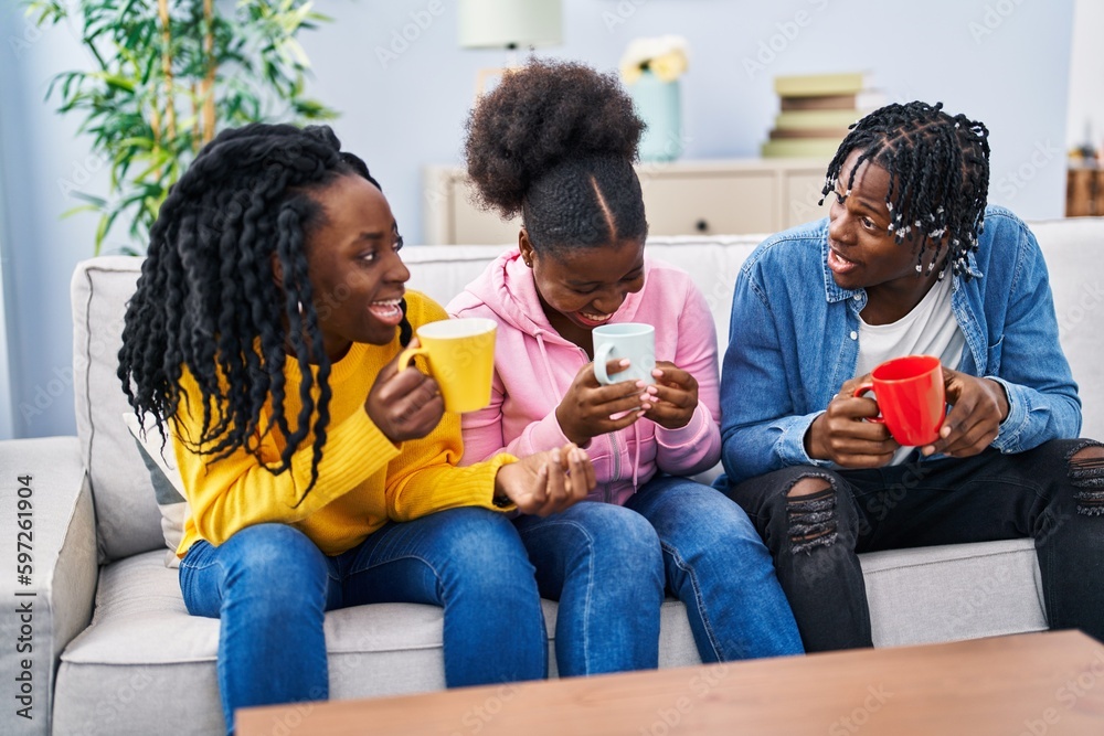 African american friends drinking coffee sitting on sofa at home African american friends drinking coffee sitting on sofa at home