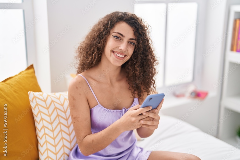 Young beautiful hispanic woman using smartphone sitting on bed at bedroom Young beautiful hispanic woman using smartphone sitting on bed at bedroom