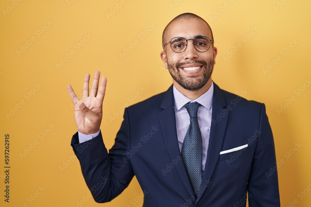 Hispanic man with beard wearing suit and tie showing and pointing up with fingers number four while smiling confident and happy. Hispanic man with beard wearing suit and tie showing and pointing up with fingers number four while smiling confident and happy.