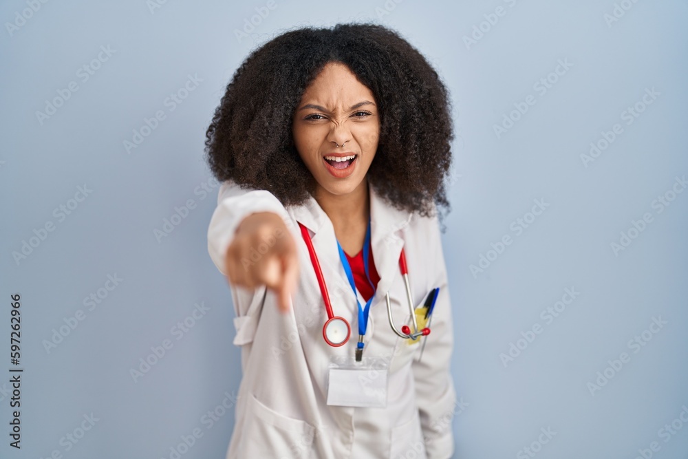 Young african american woman wearing doctor uniform and stethoscope pointing displeased and frustrated to the camera, angry and furious with you Young african american woman wearing doctor uniform and stethoscope pointing displeased and frustrated to the camera, angry and furious with you