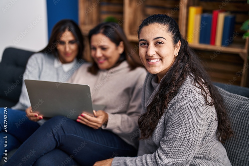 Three woman using laptop sitting on sofa at home Three woman using laptop sitting on sofa at home