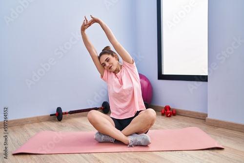 Young woman smiling confident stretching arms at sport center